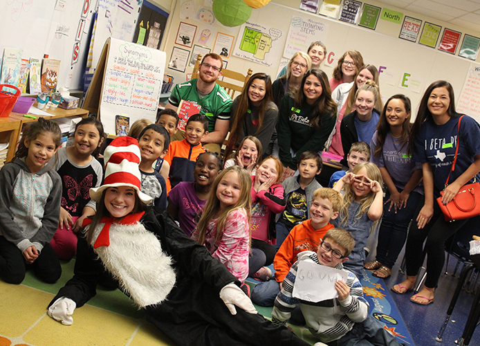 Students posing with a teacher in cat in hat ofit