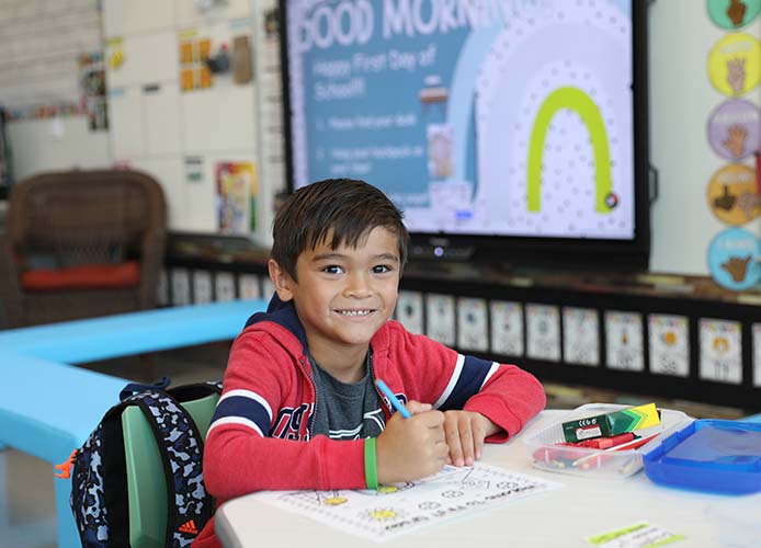 Student writing and smiling